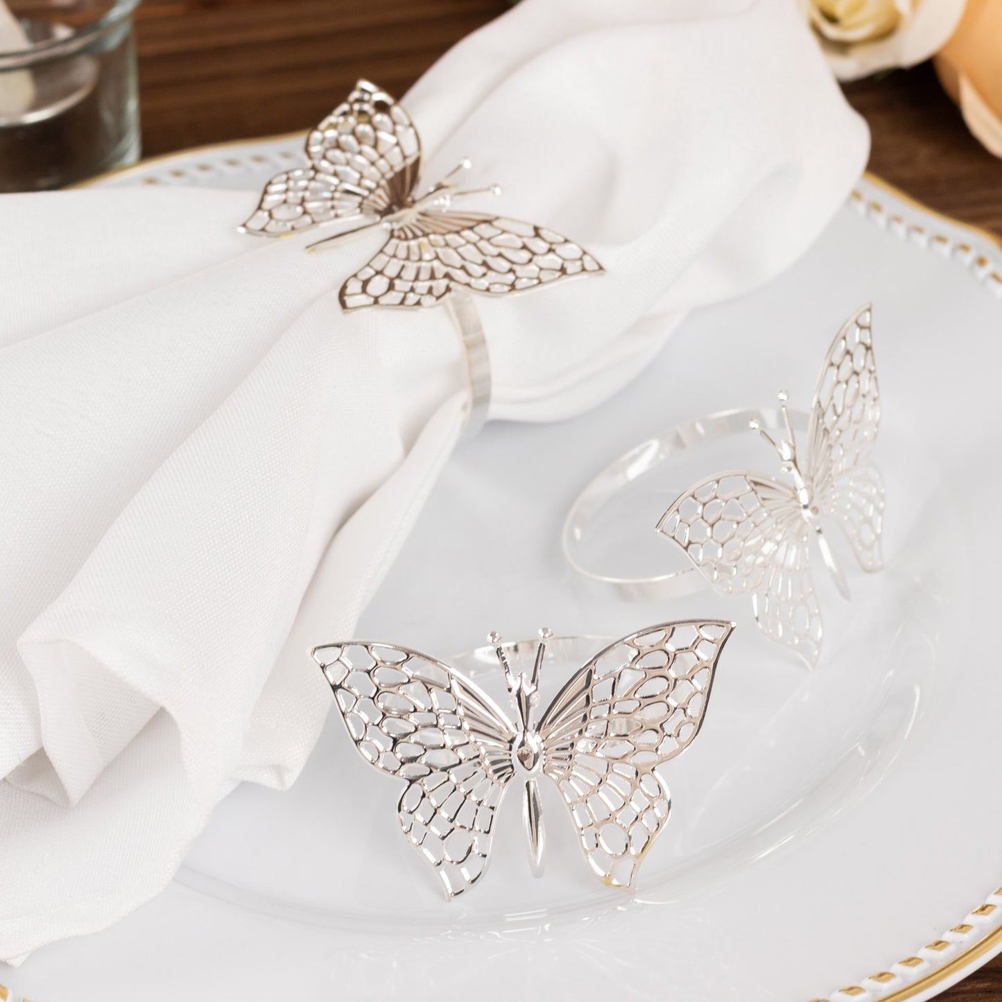 Silver metal butterfly napkin rings on a white napkin.