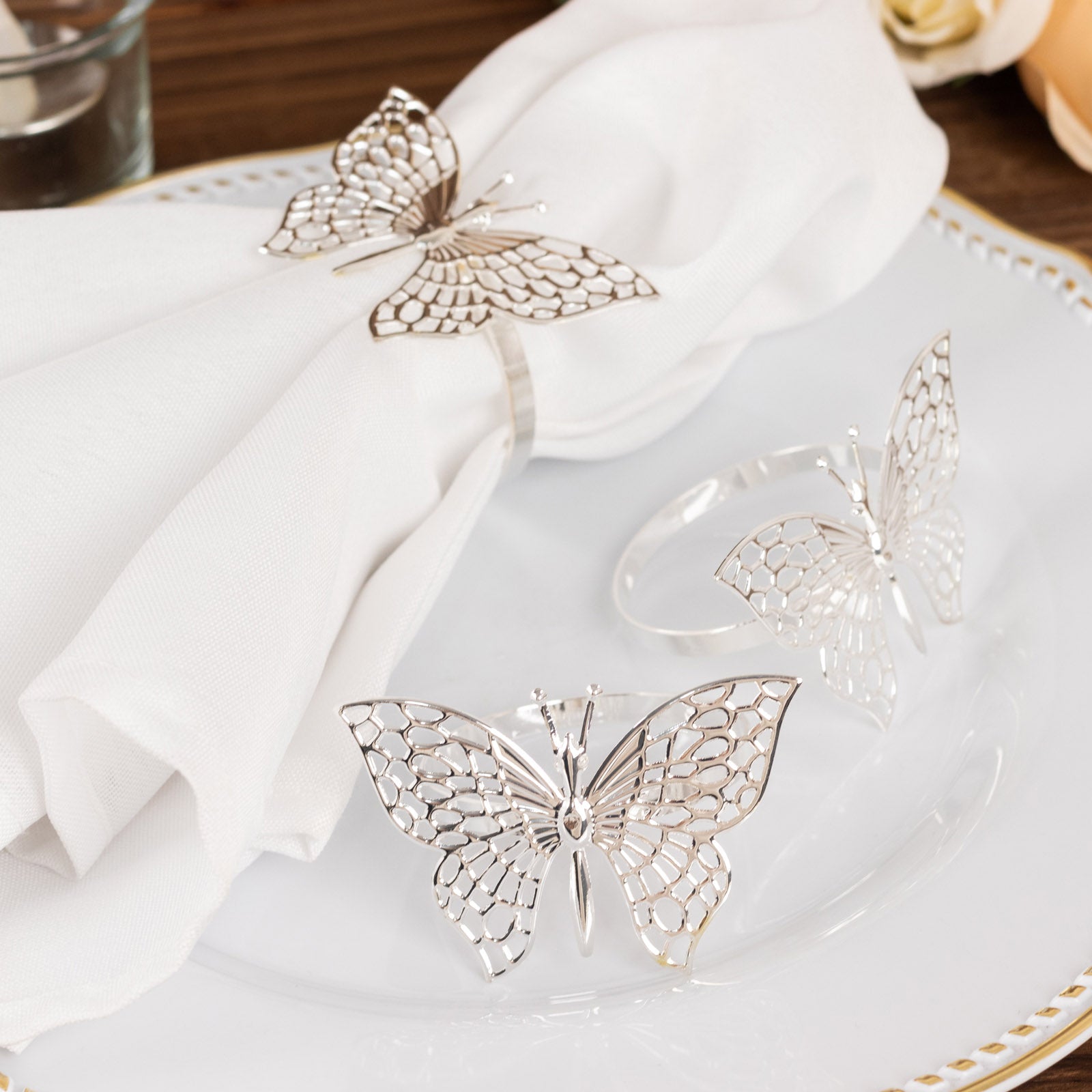 Silver metal butterfly napkin rings on a white napkin.