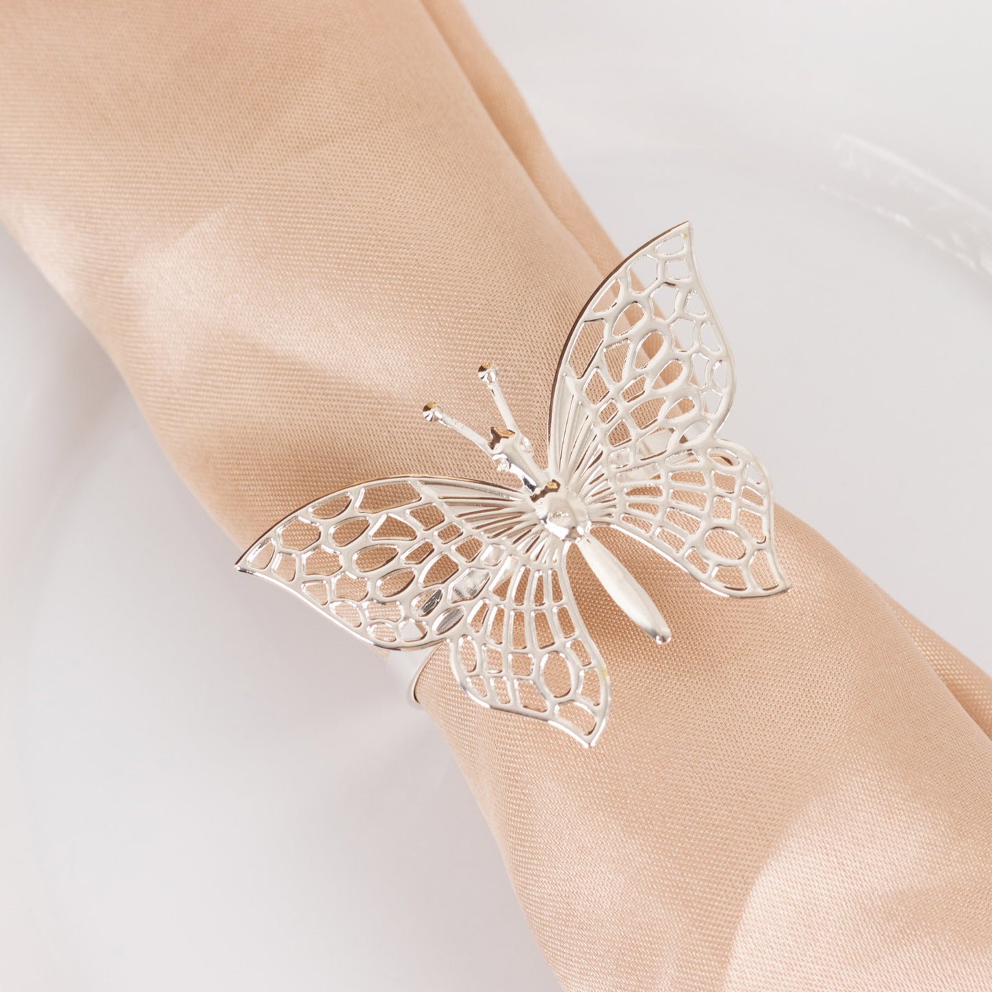 Silver butterfly napkin ring holder on a beige napkin.