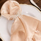Silver metal butterfly napkin ring holding a soft beige napkin.