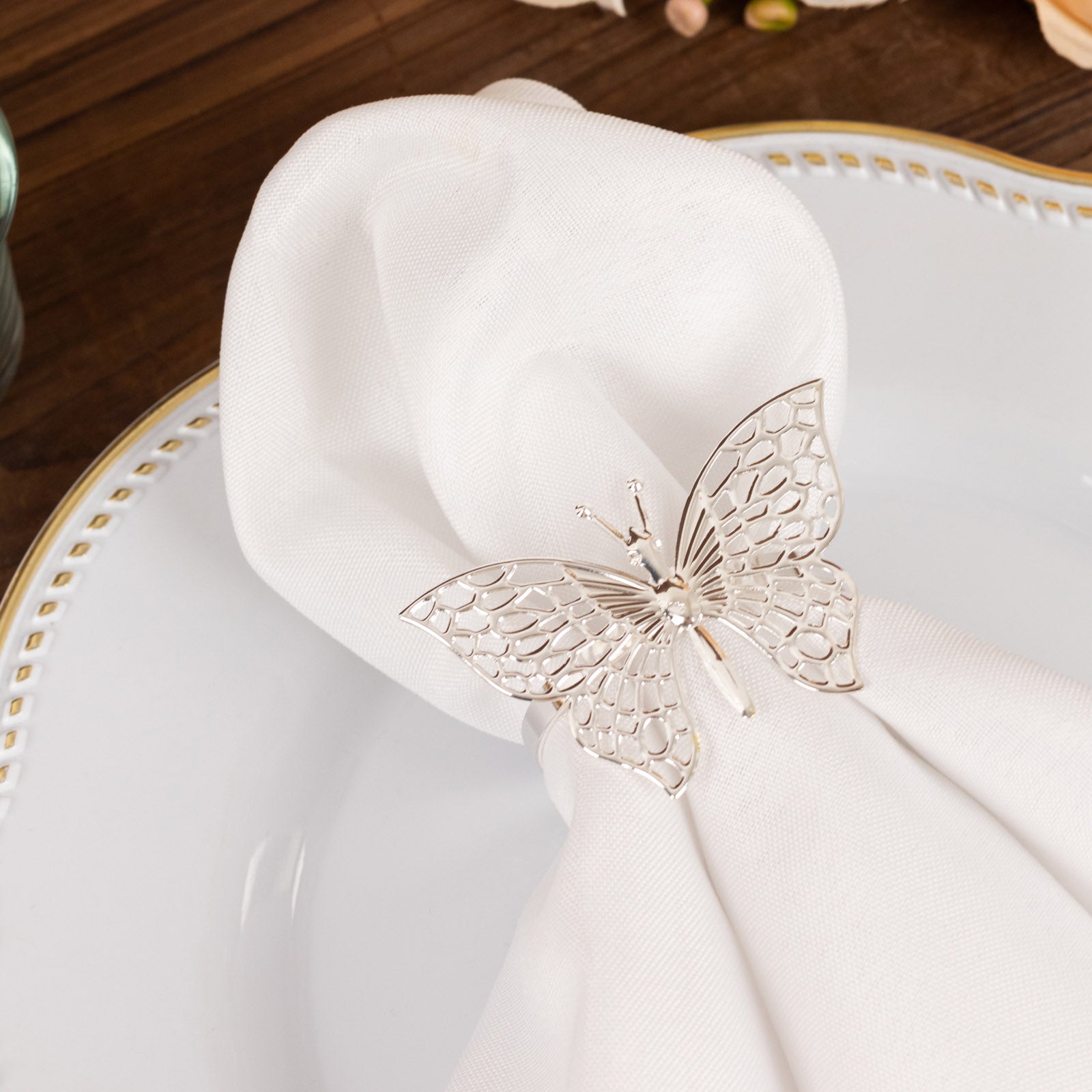 Silver metal butterfly napkin ring on a white cloth napkin.