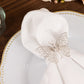 Silver metal butterfly napkin rings on a white cloth napkin.
