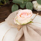 Blush artificial rose napkin holder with rustic twine on a plate.