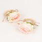 Blush artificial rose flower napkin holders with wooden rings.