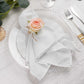 Blush artificial rose wooden napkin holder on a white plate setting.