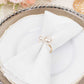 White pearl and gold metal napkin holder on a dining table setting.