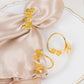 Gold butterfly metal napkin holders on a beige napkin, elegant dining table decor.