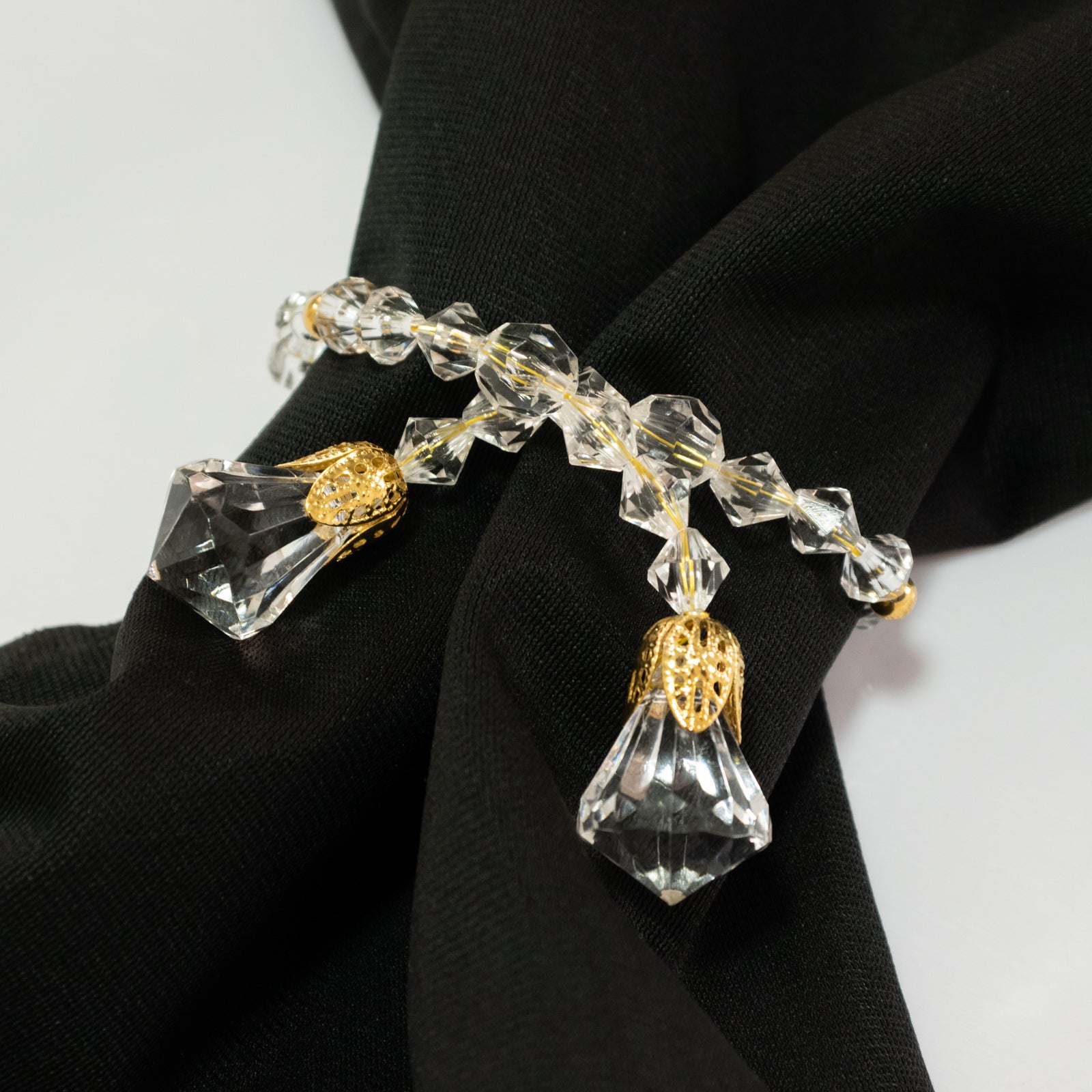 Clear crystal beaded napkin ring with gold accents on a black napkin.