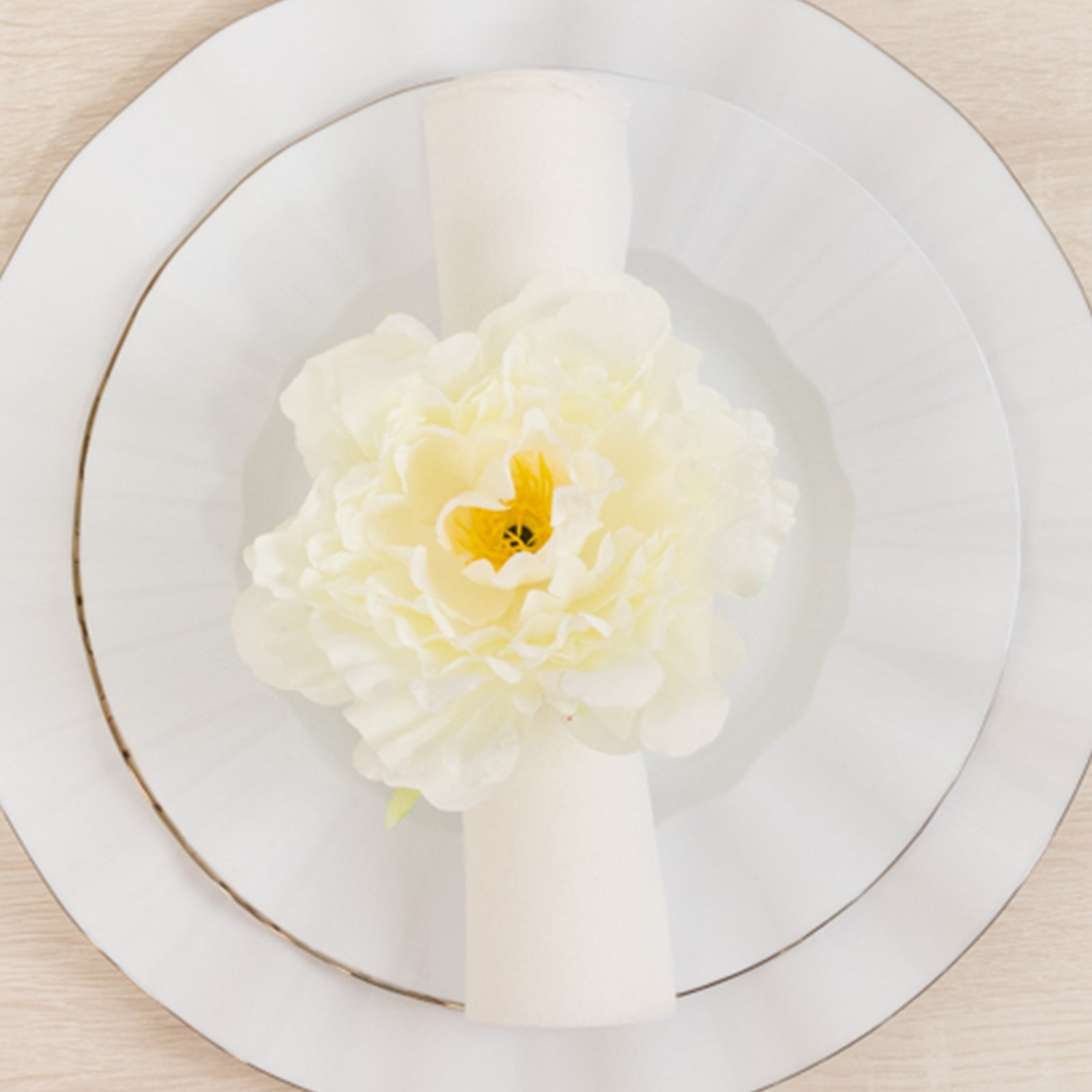 Ivory floral napkin holder with silk peony flower on a dining plate.