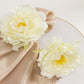 Ivory floral napkin holders with silk peony flowers for dining table settings.