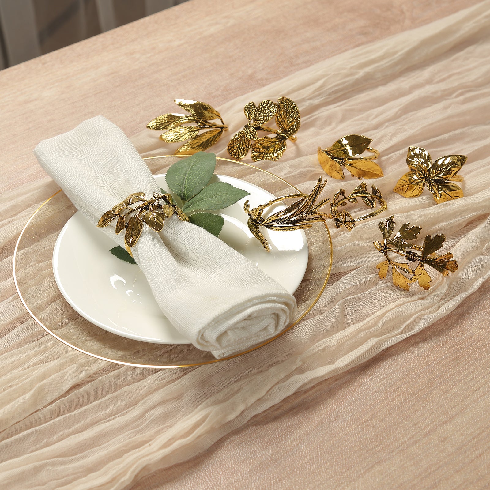 Glossy gold metal leaf napkin rings on a table setting with a napkin.
