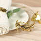 Glossy gold metal leaf napkin rings with vintage herb design.