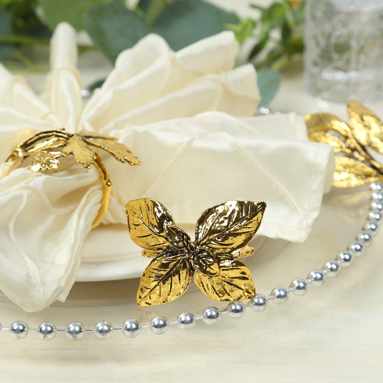 Glossy gold metal leaf napkin rings with vintage herb design.