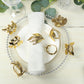 Glossy gold vintage herb napkin rings on a table setting.