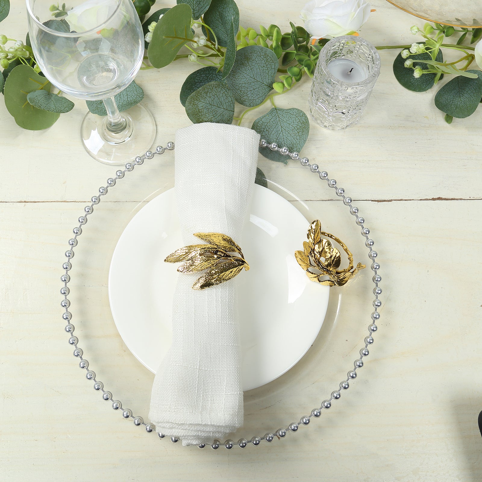Glossy gold metal leaf napkin rings on a white plate with a napkin.