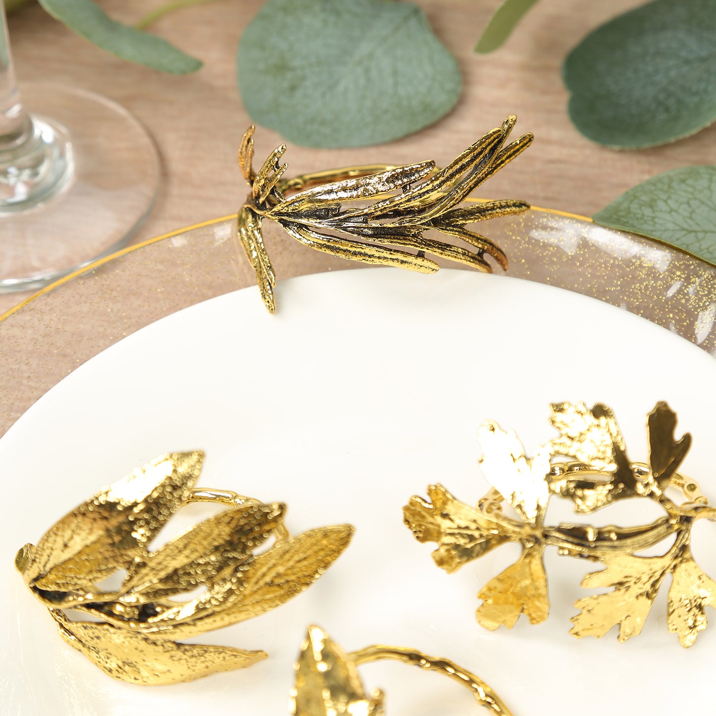 Glossy gold vintage herb metal leaf napkin rings on a plate.