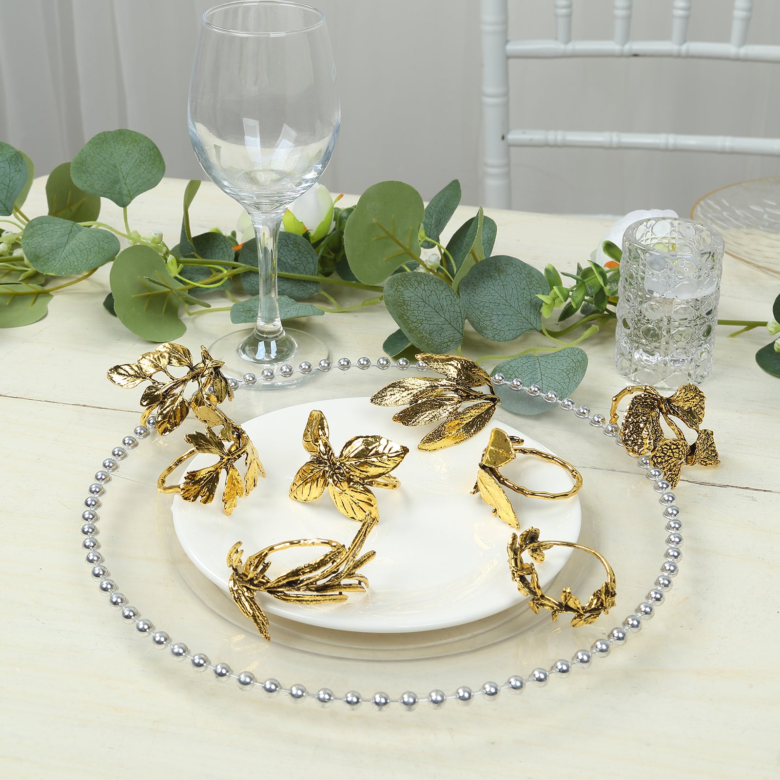 Glossy gold metal leaf napkin rings on a decorative plate.