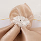 Silver metal jasmine flower napkin holder with pearl center on beige napkin.