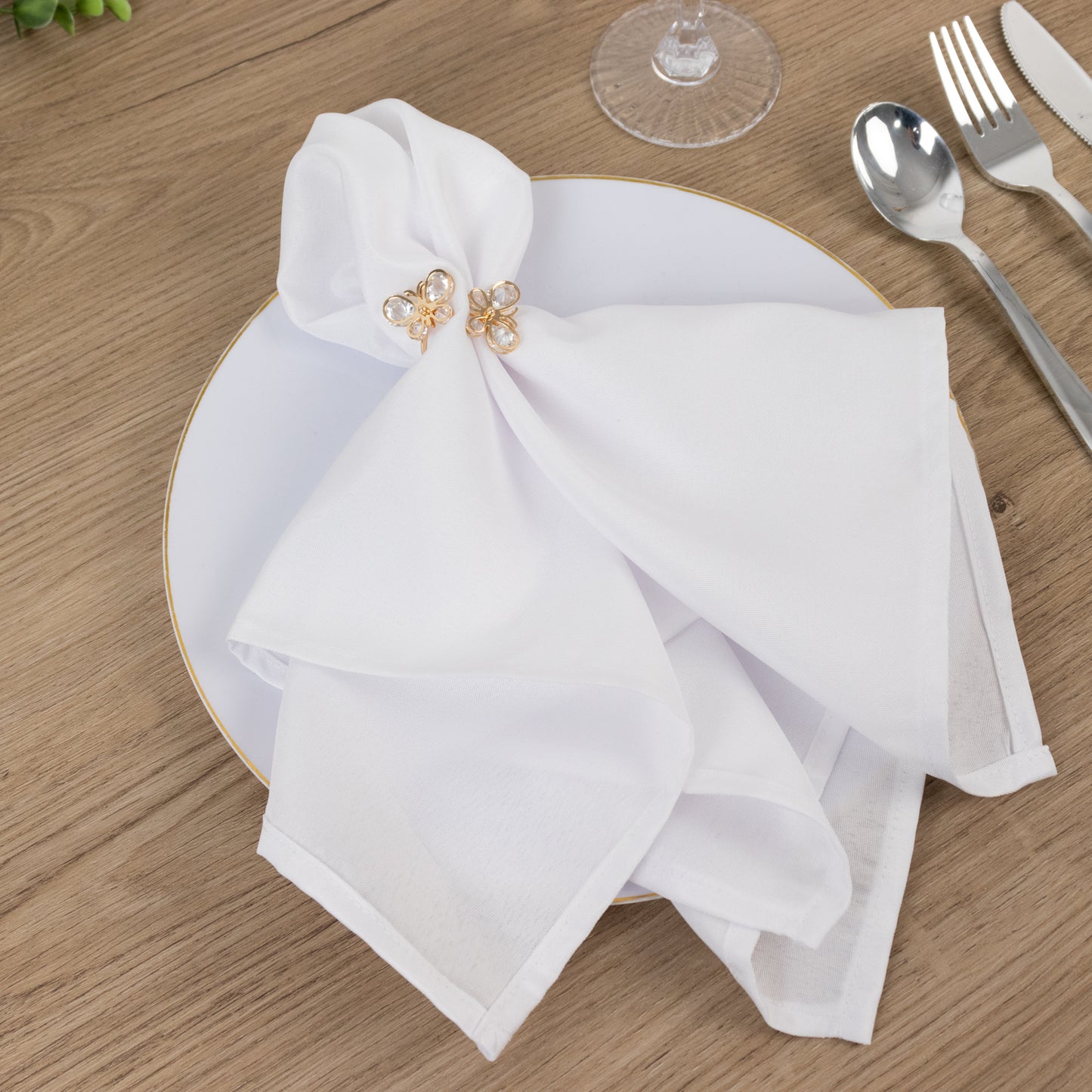 Gold butterfly napkin holders with crystal accents on a white napkin.