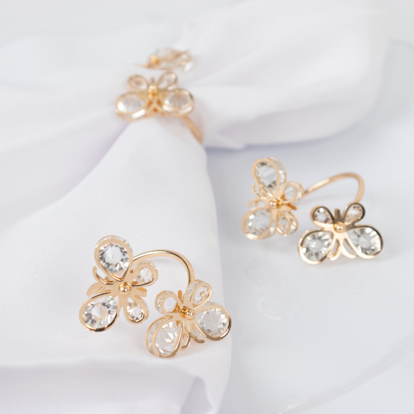 Gold butterfly napkin holders with crystal accents on white napkins.