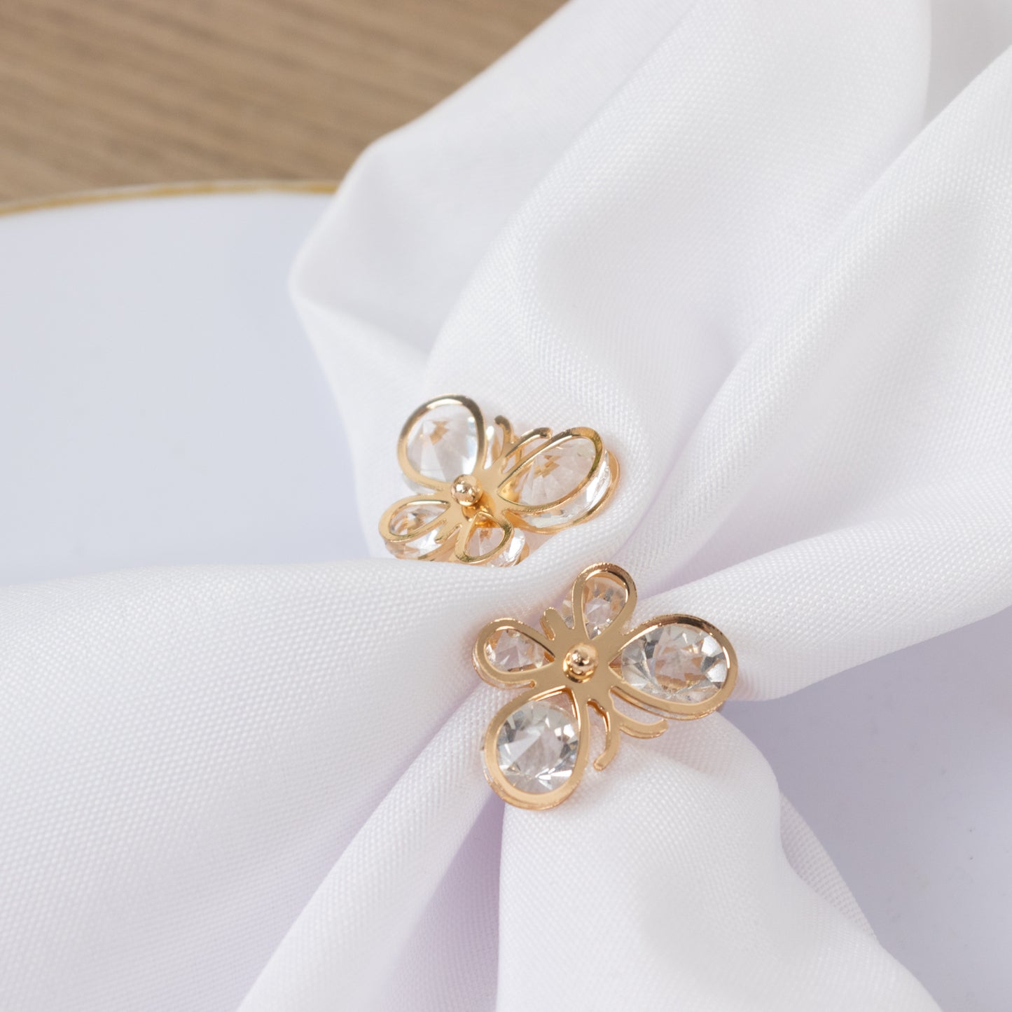 Gold butterfly napkin holders with crystal accents on white napkin.