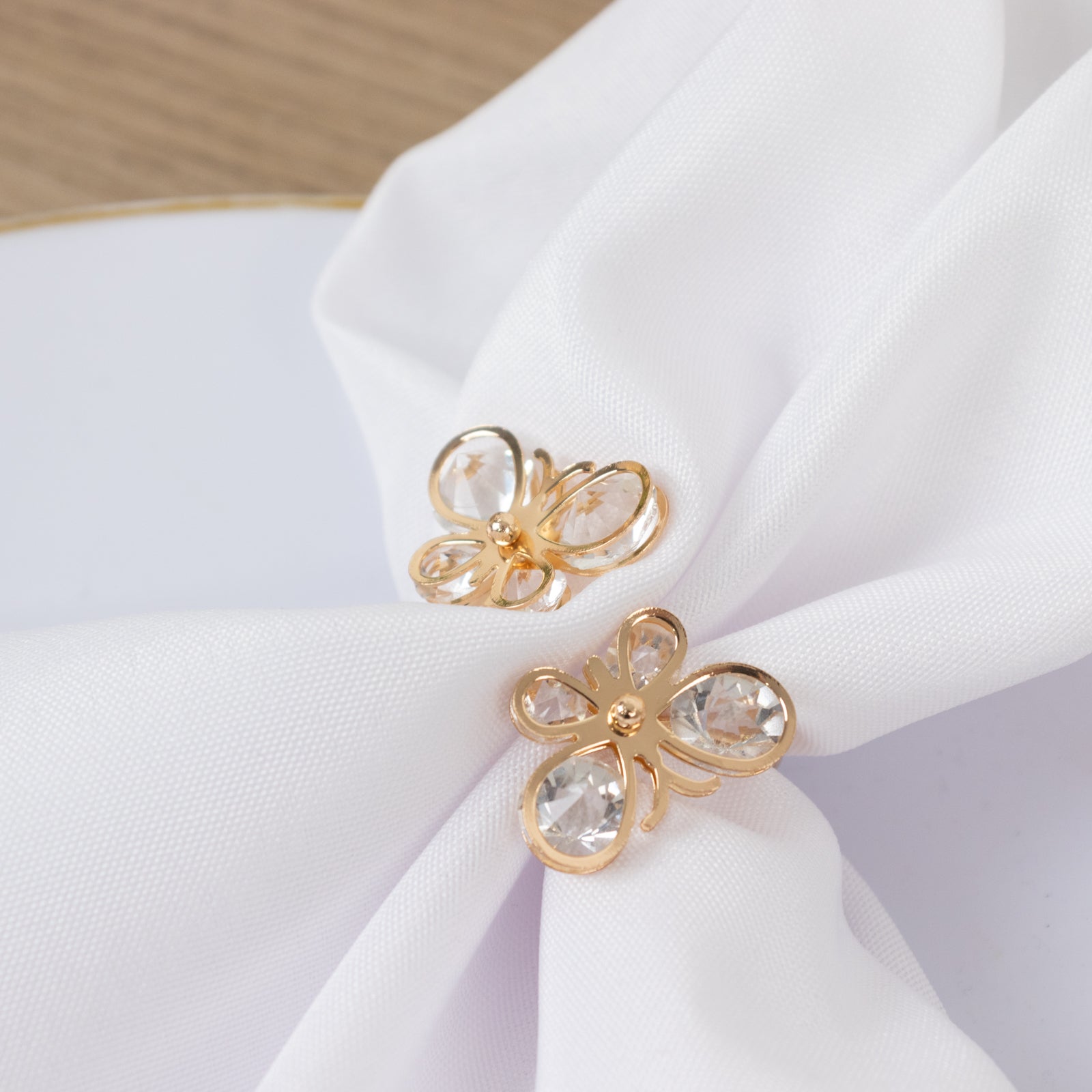 Gold butterfly napkin holders with crystal accents on white napkin.