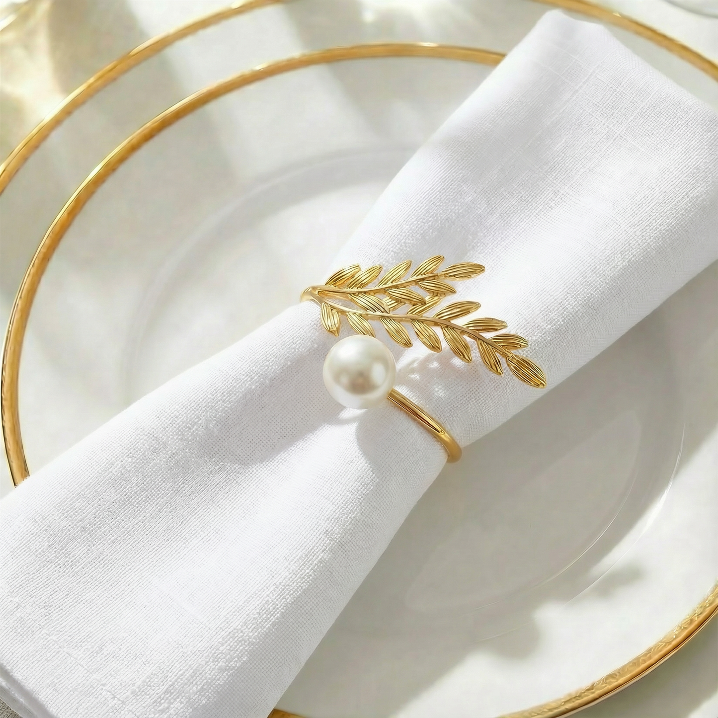 Gold napkin ring with white pearl accent on white napkin.