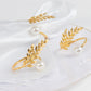 Gold leaf napkin rings with white pearl accent on a white napkin.