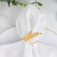 Gold leaf napkin ring with white pearl accent on a white napkin.
