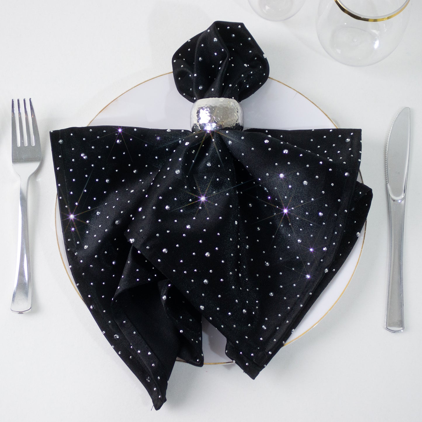 Black scuba polyester napkin with rhinestone accents on a plate.