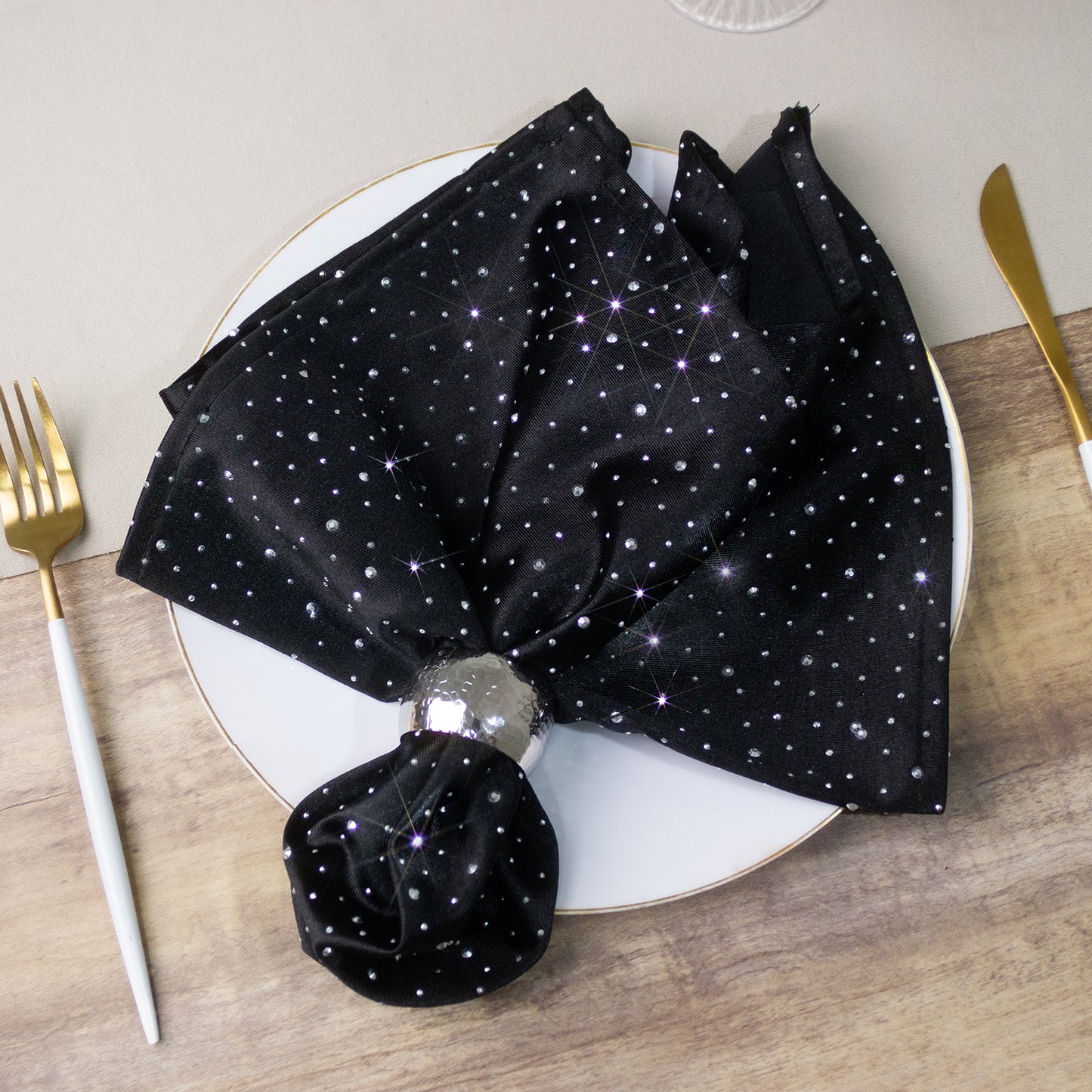 Black scuba polyester napkin with rhinestone accents on a plate.