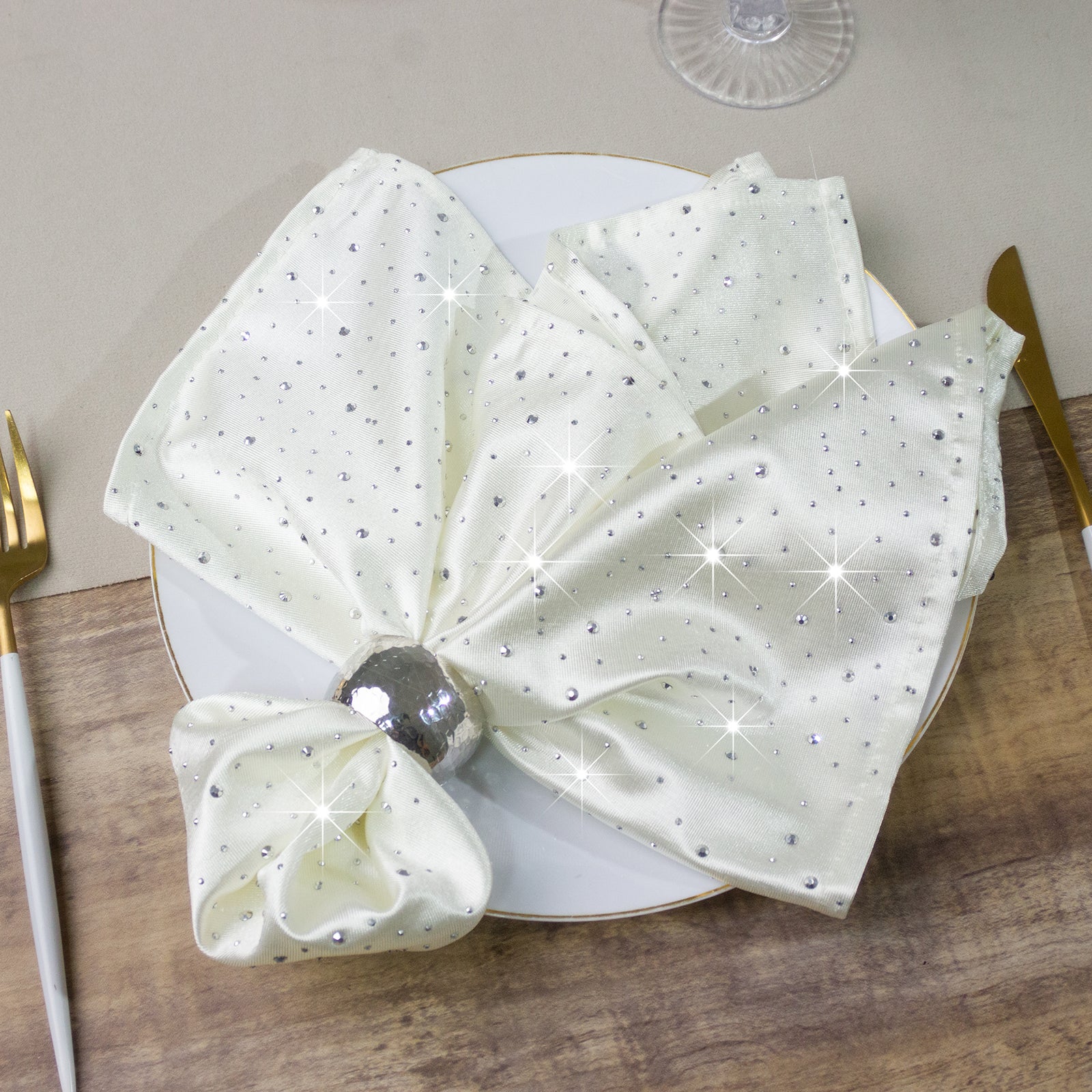Pearl white reusable cloth napkins with rhinestone accents on a table setting.