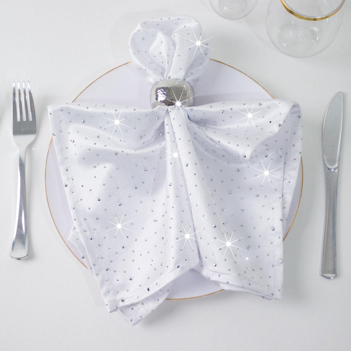White scuba polyester napkin with rhinestone accents on a dining plate.