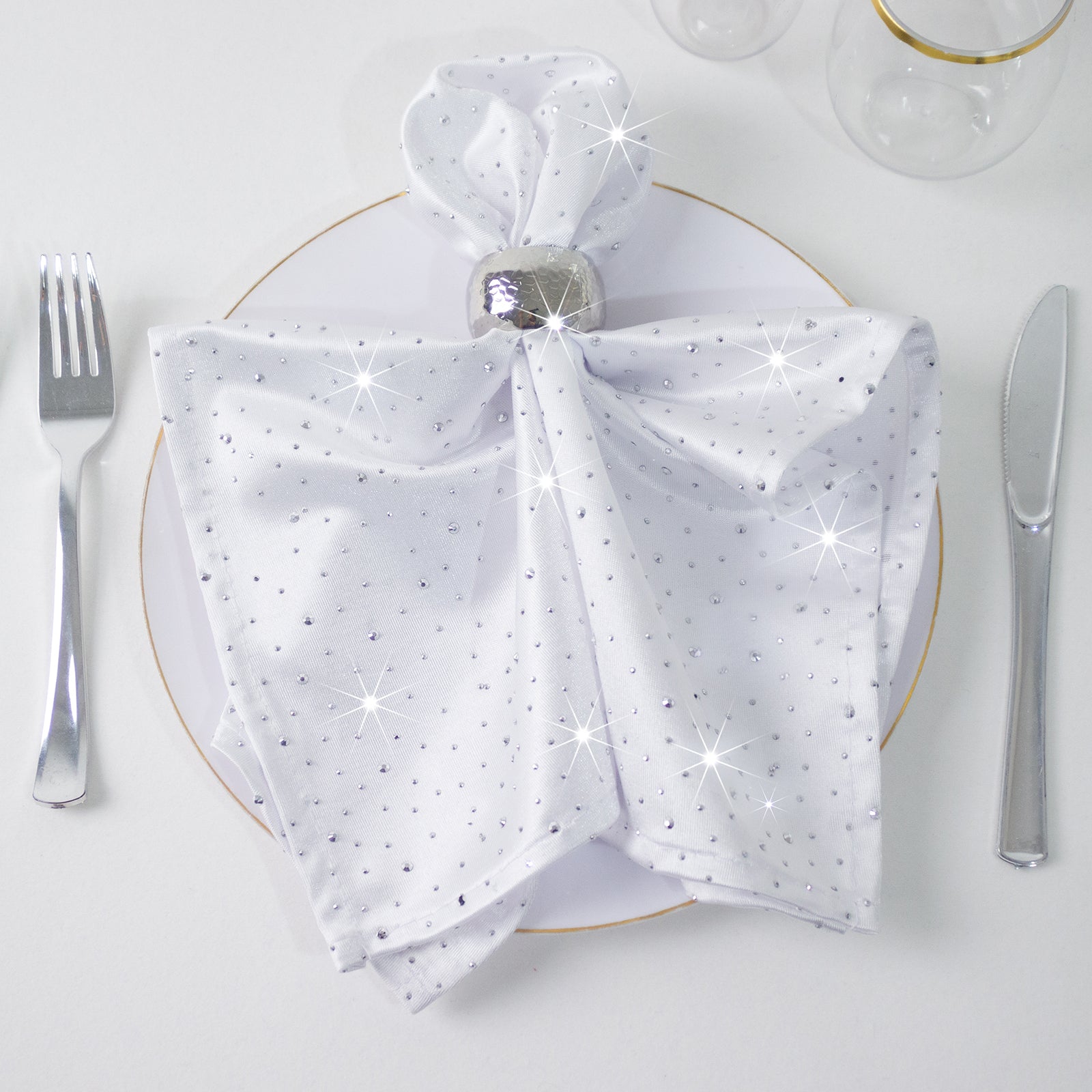 White scuba polyester napkin with rhinestone accents on a dining plate.
