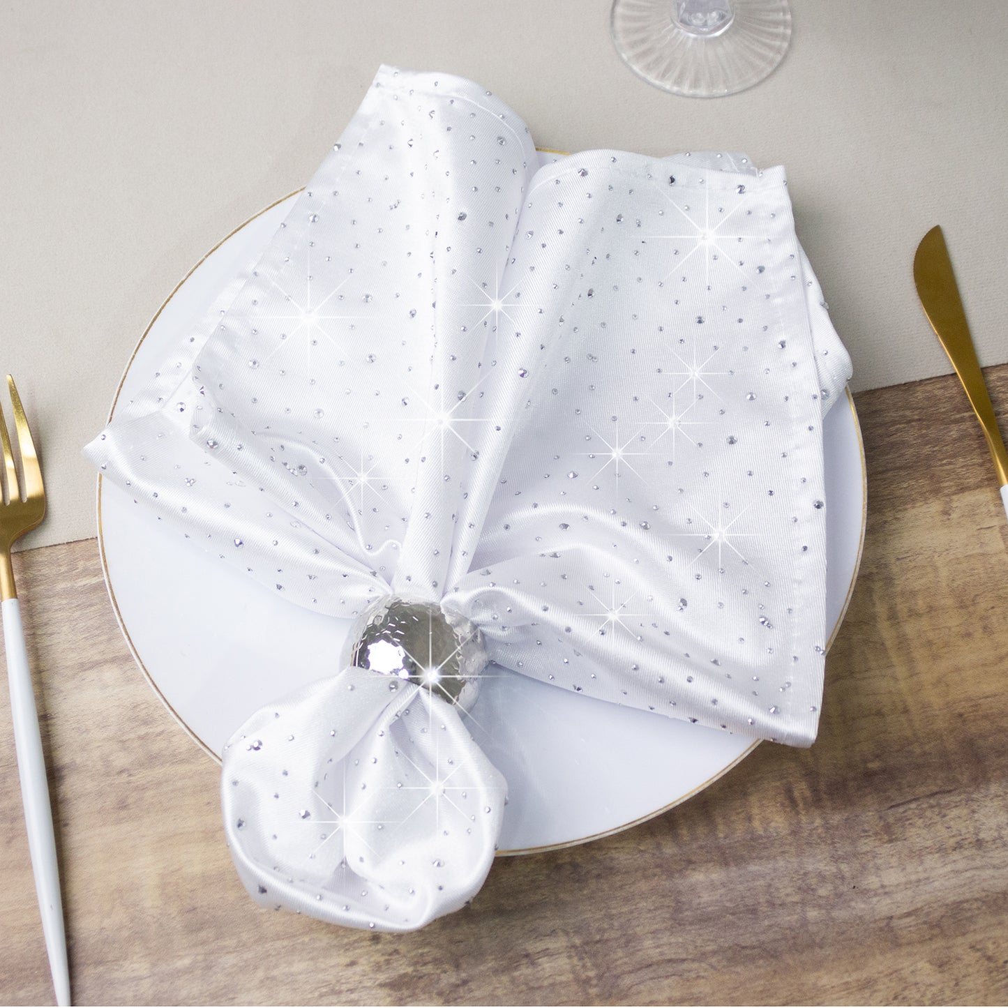 White scuba polyester napkin with rhinestone accents on a plate.