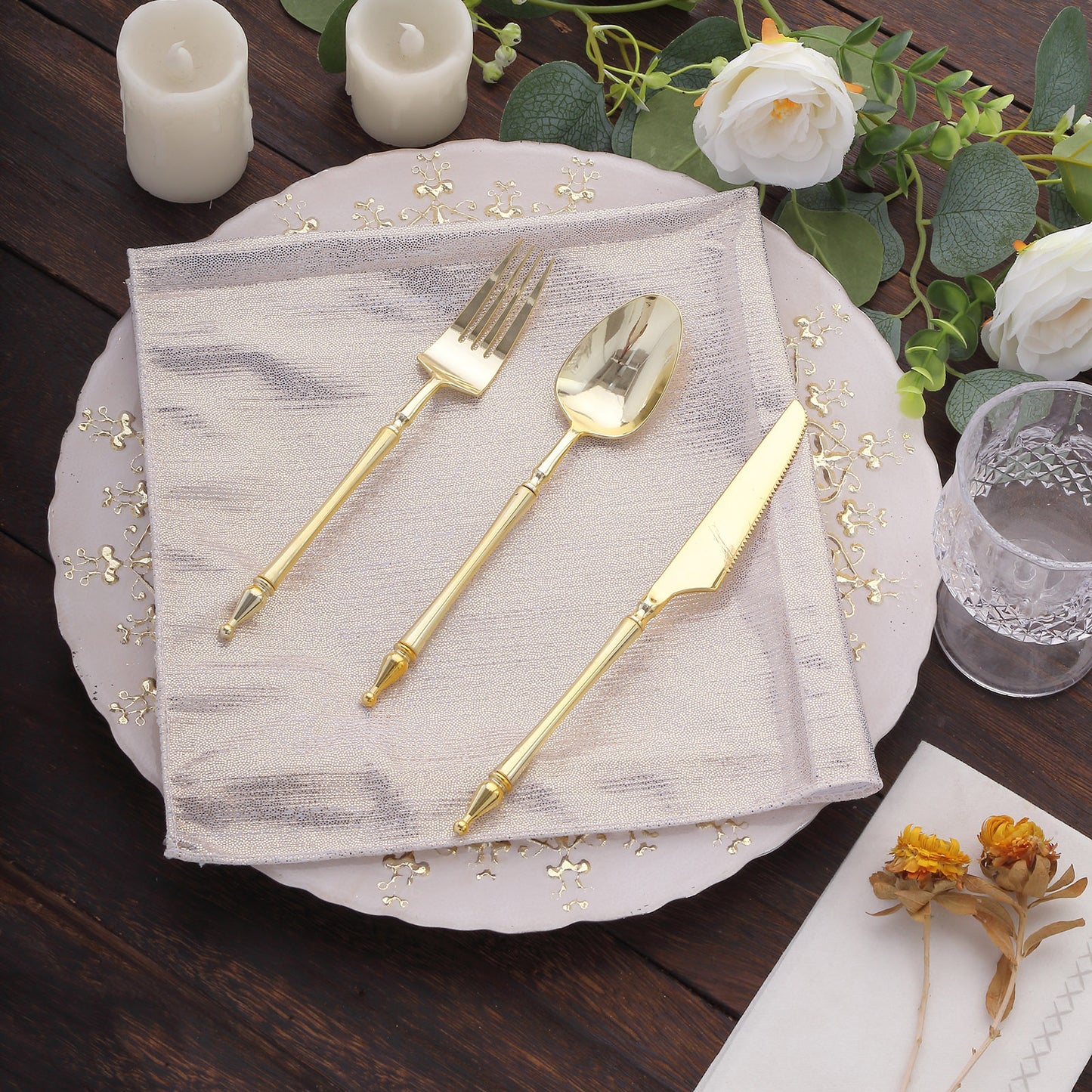 Beige shimmer sequin dot table napkin with gold utensils and floral decor.