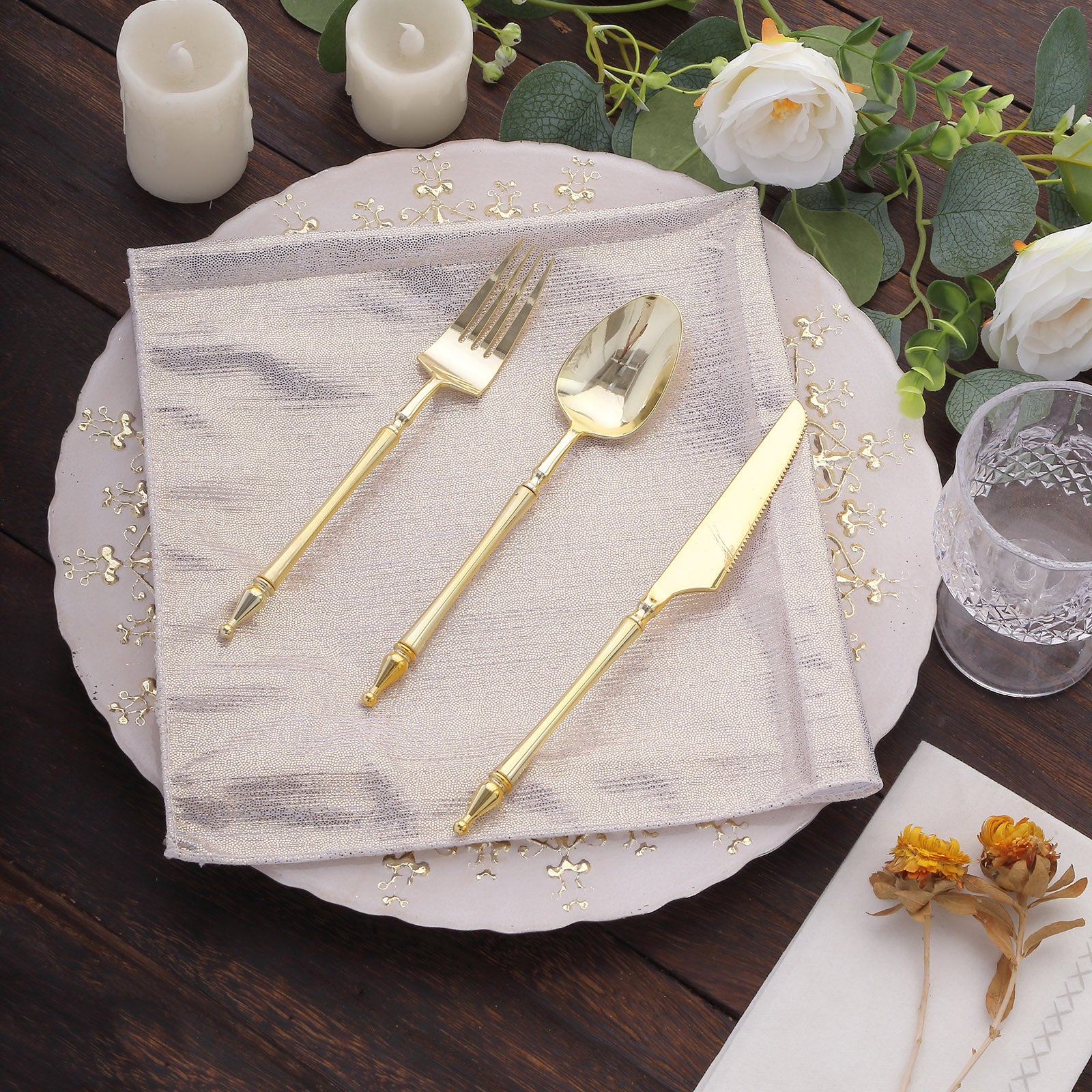 Beige shimmer sequin dot table napkin with gold utensils and floral decor.