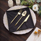 Black shimmer sequin table napkin with gold utensils on a decorative plate.