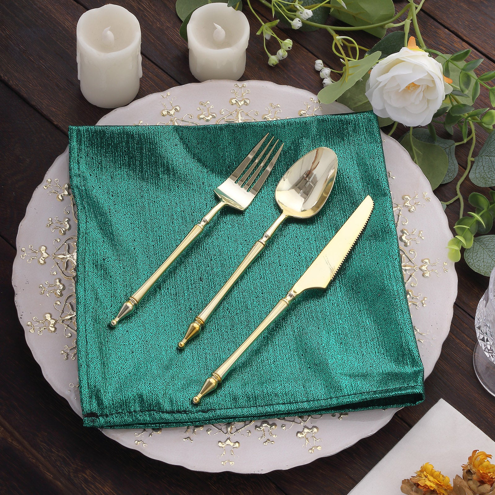 Emerald green shimmer sequin table napkin with gold utensils on a decorative plate.