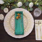 Emerald green shimmer sequin table napkin on a decorative plate.