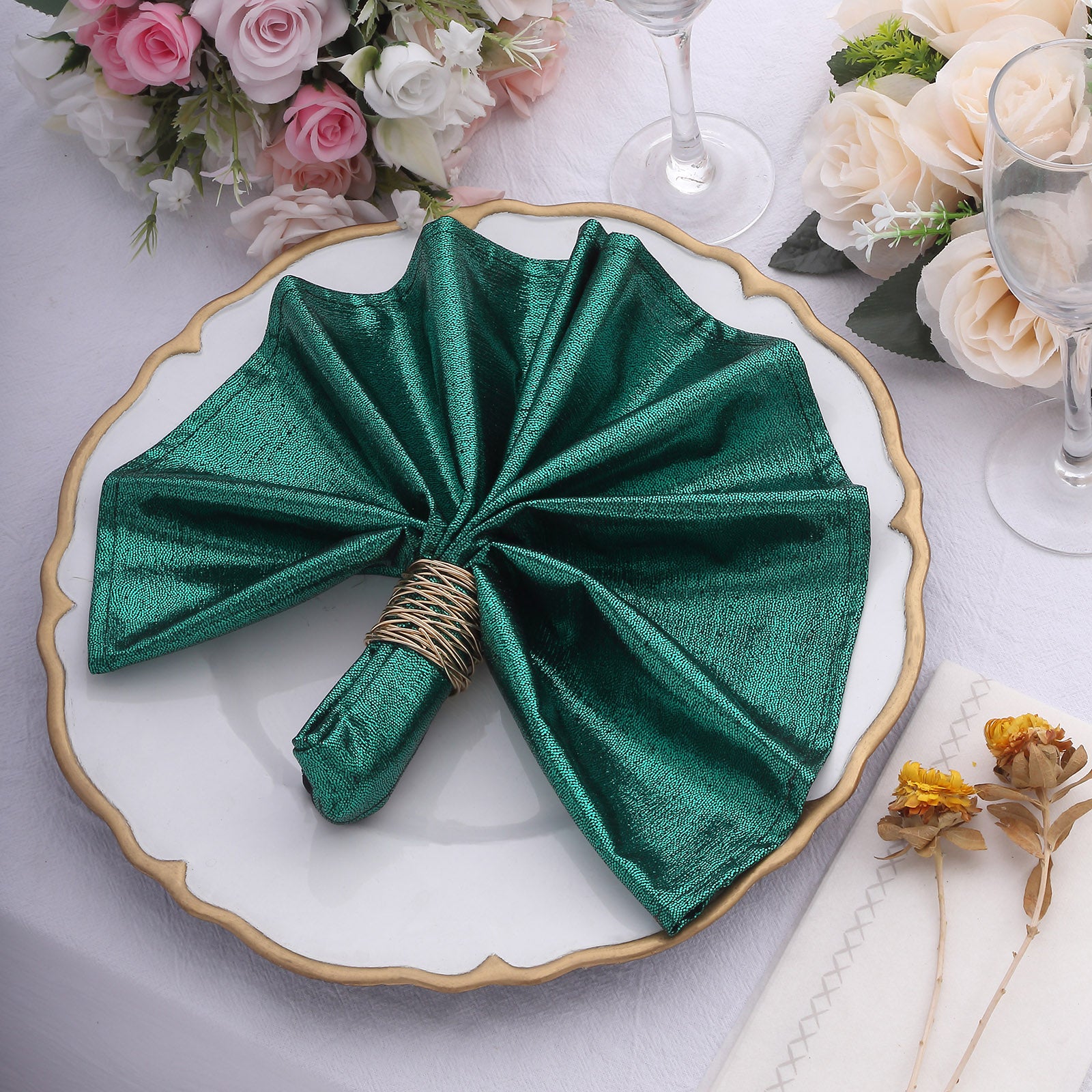 Emerald green shimmer sequin table napkin elegantly displayed on a dinner plate.