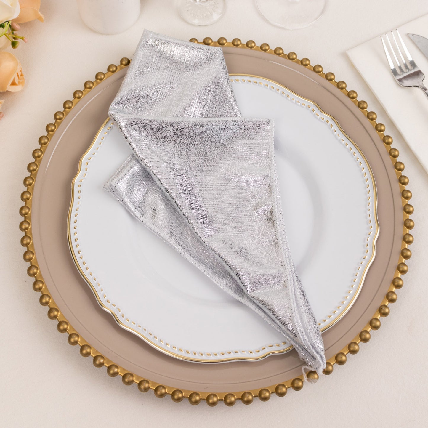 Silver shimmer sequin napkin on a decorative plate setting.