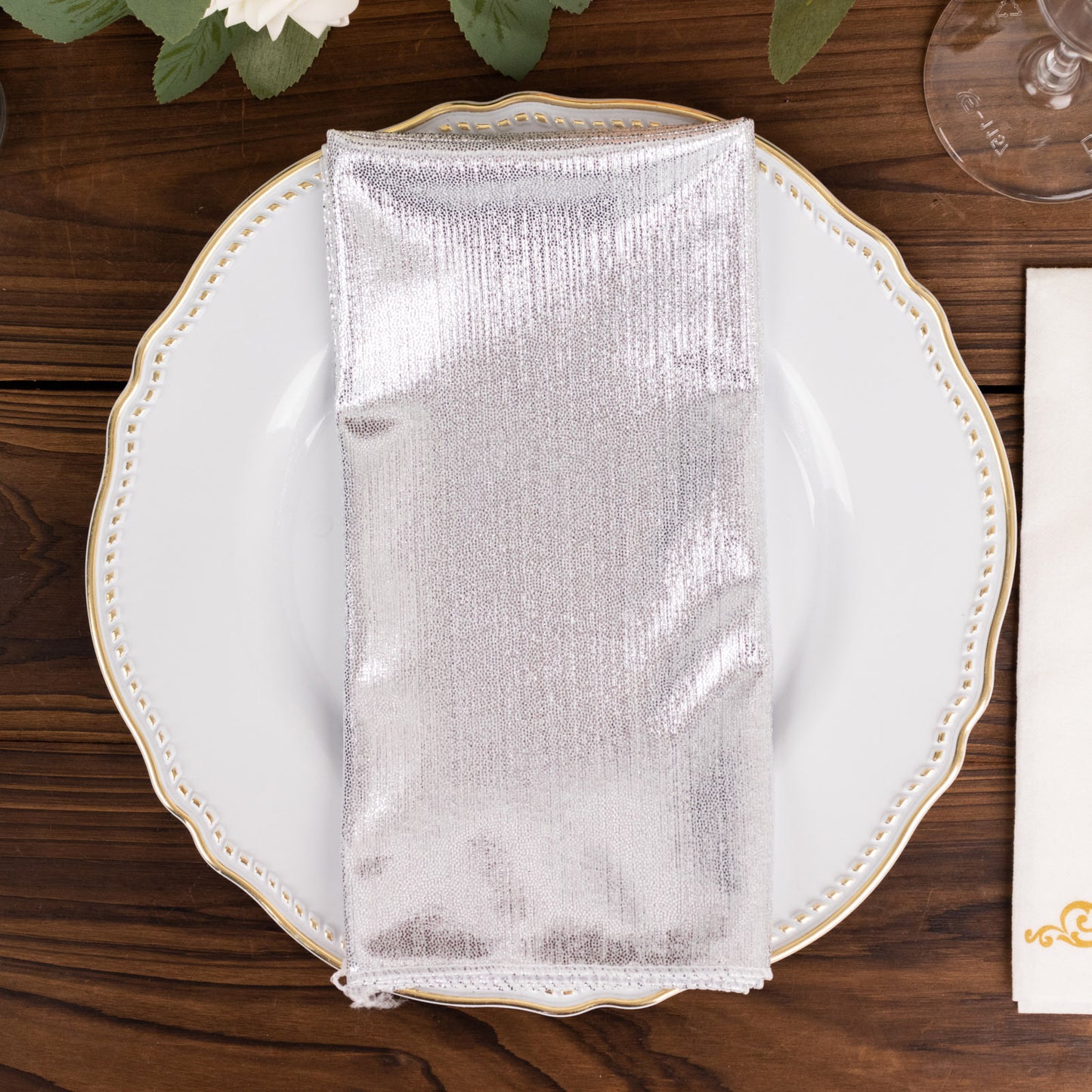 Silver shimmer sequin cloth napkin on a decorative plate.