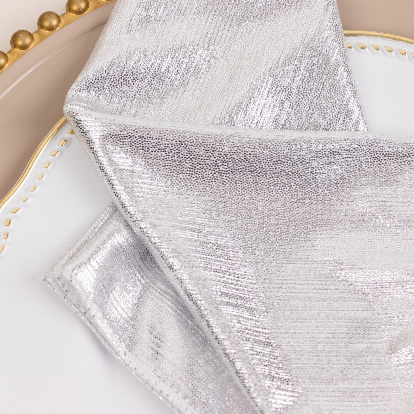 Silver shimmer sequin cloth napkins on a decorative plate.