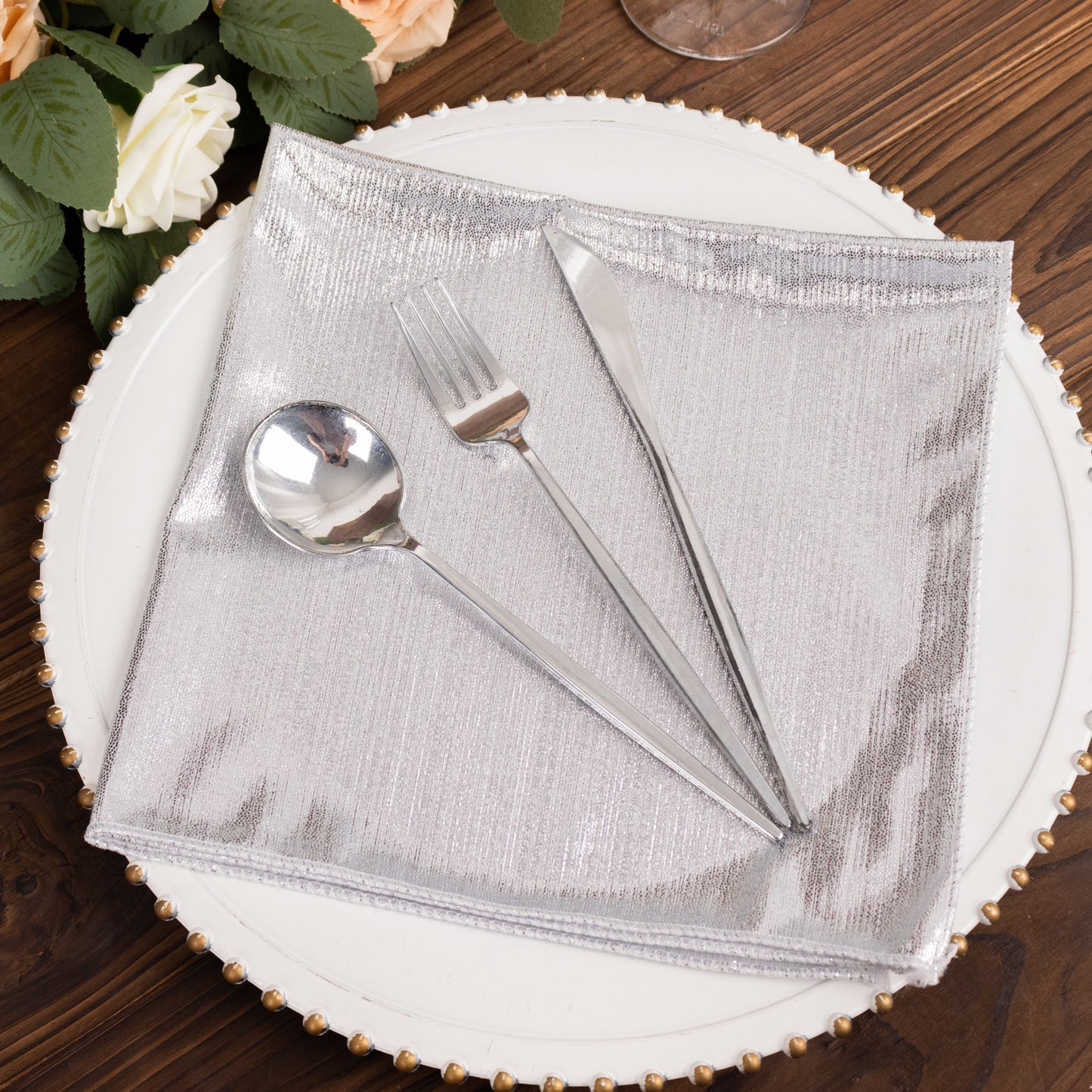 Silver shimmer sequin dots table napkin with utensils on a decorative plate.
