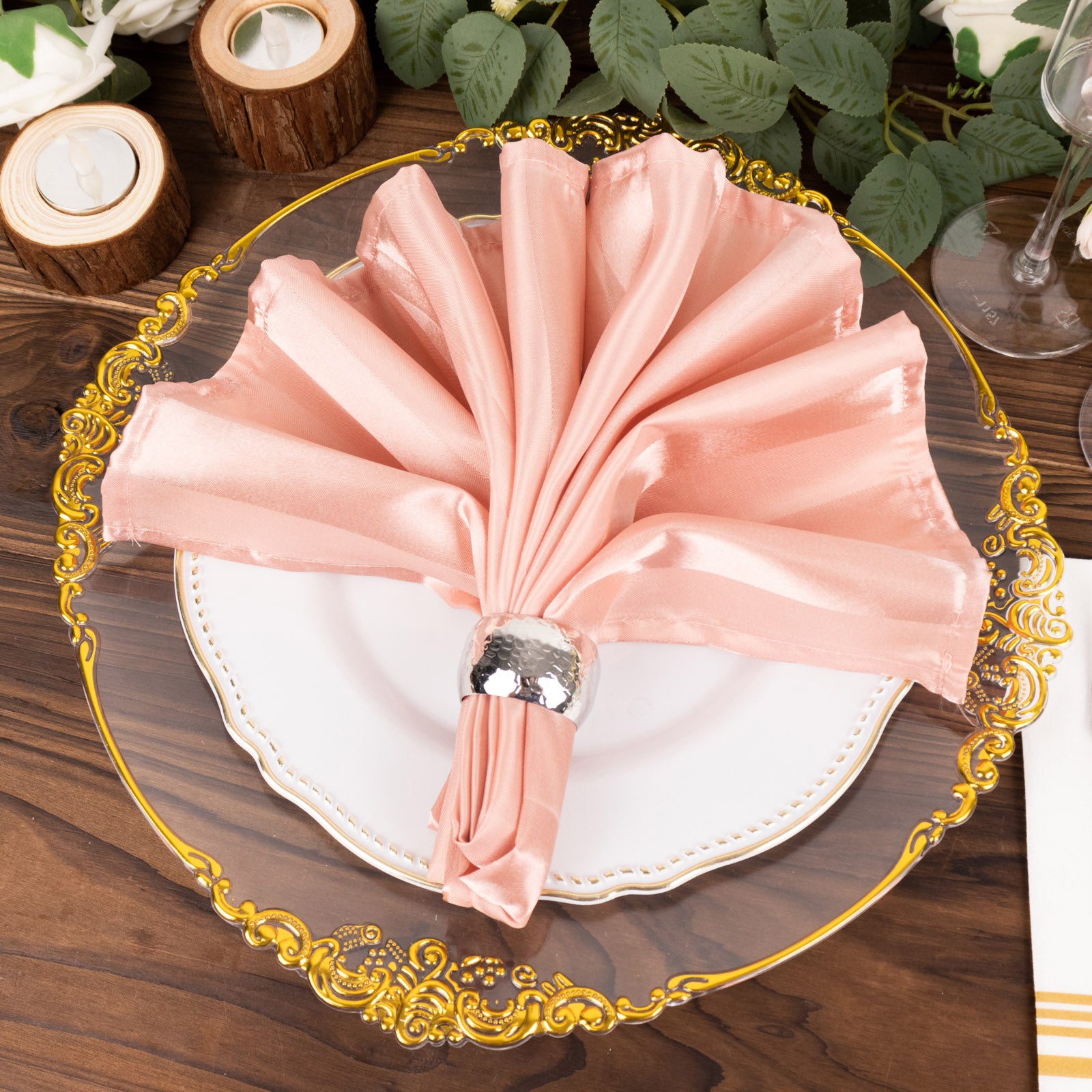 Dusty rose satin linen napkin elegantly folded on a decorative plate.