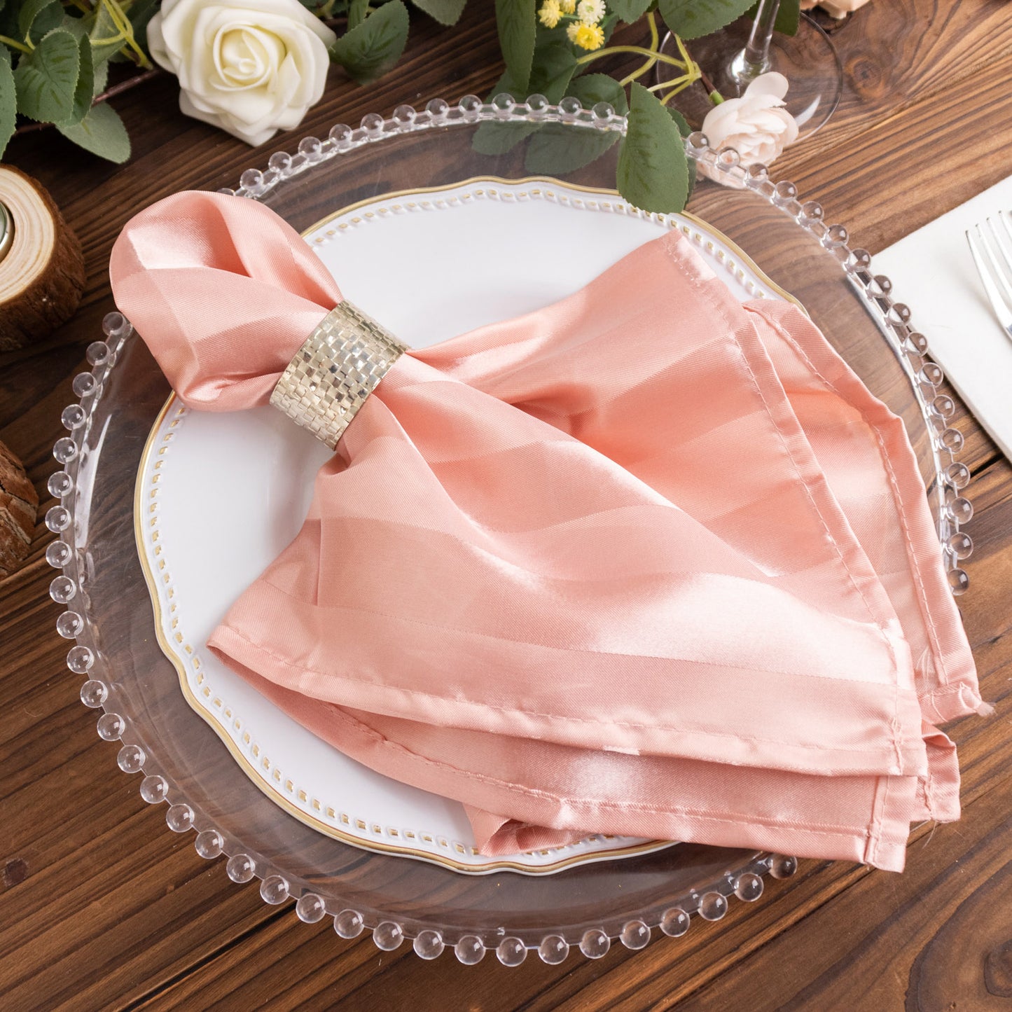 Dusty rose striped satin linen napkins on a decorative plate.