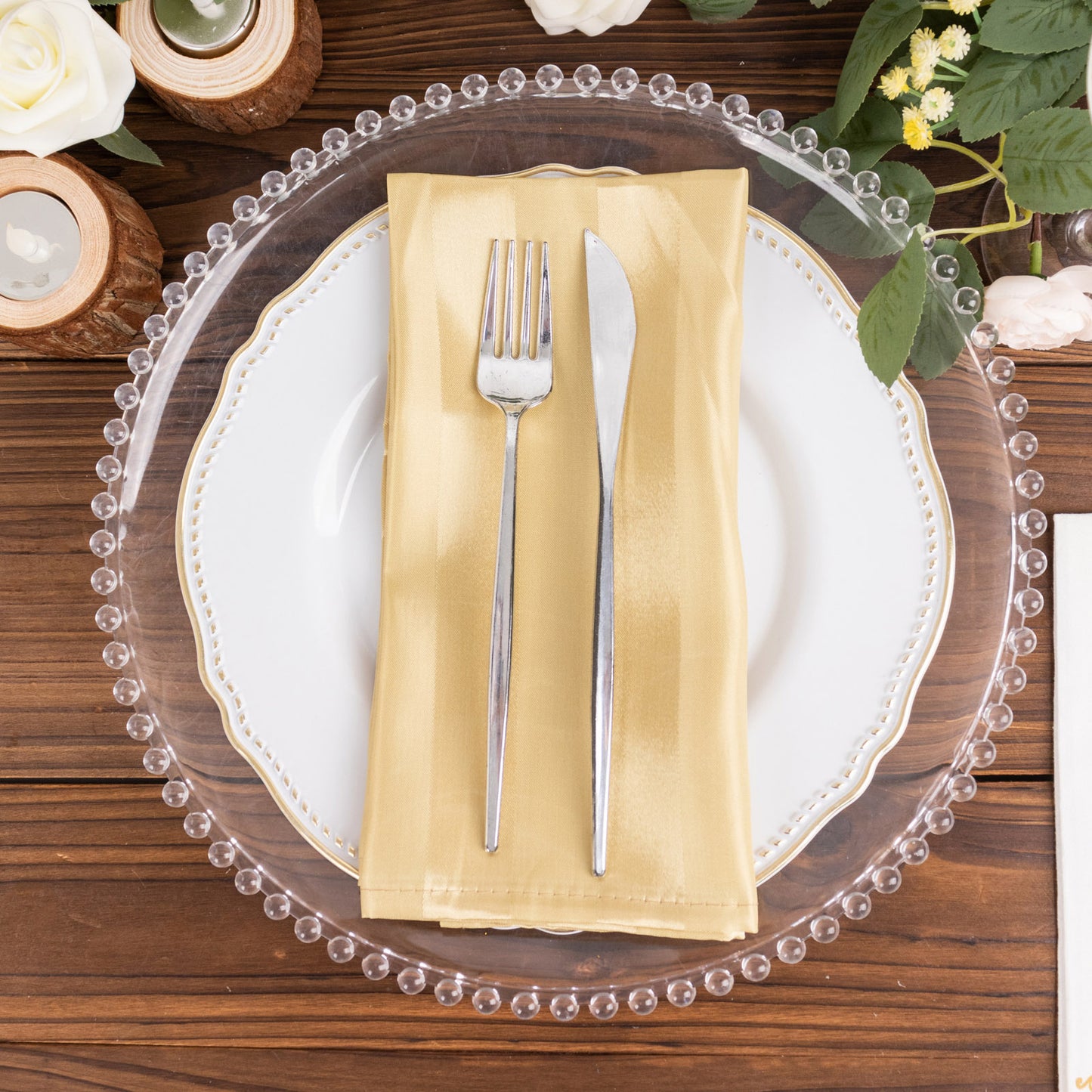 Champagne satin linen napkin on a white plate with silver cutlery.