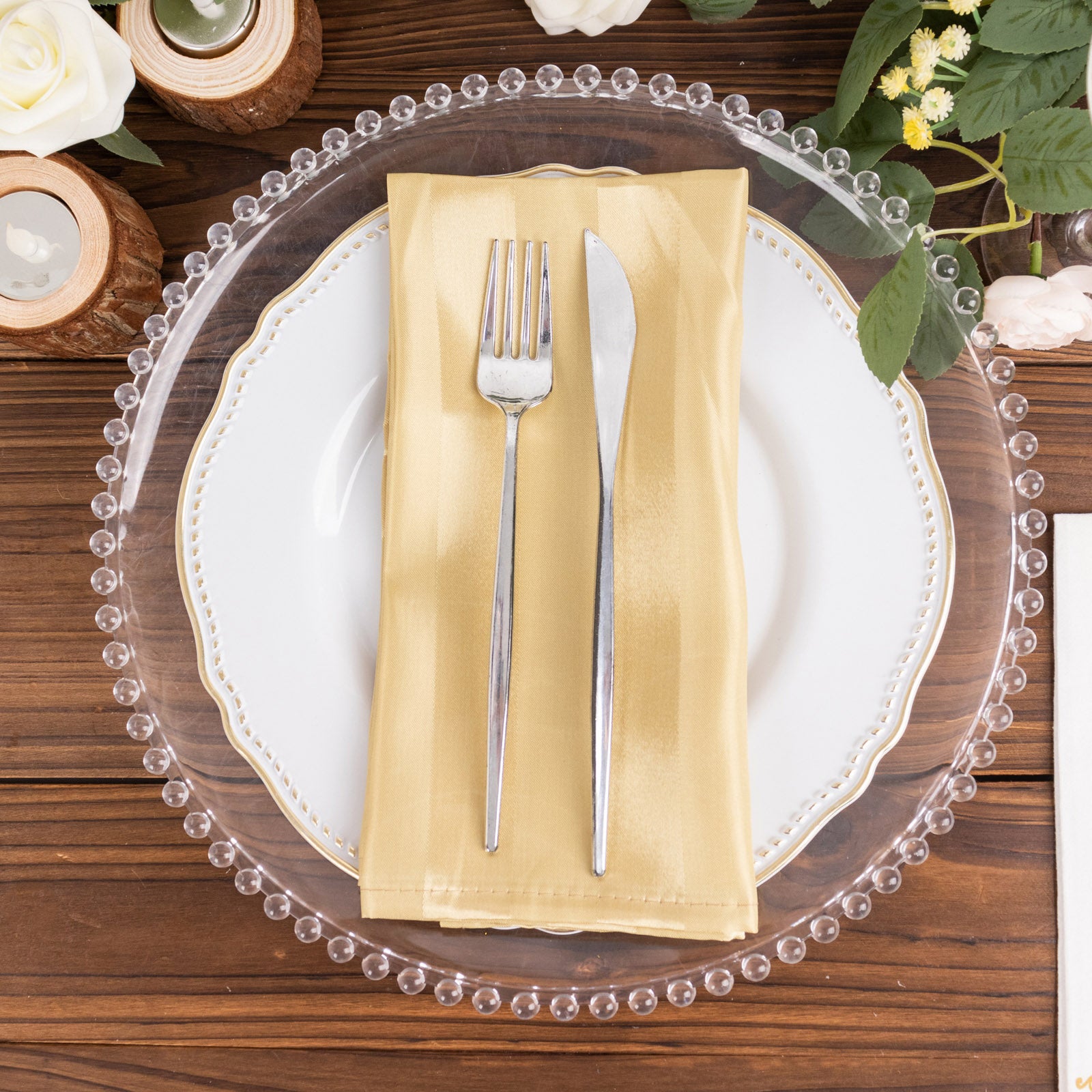 Champagne satin linen napkin on a white plate with silver cutlery.