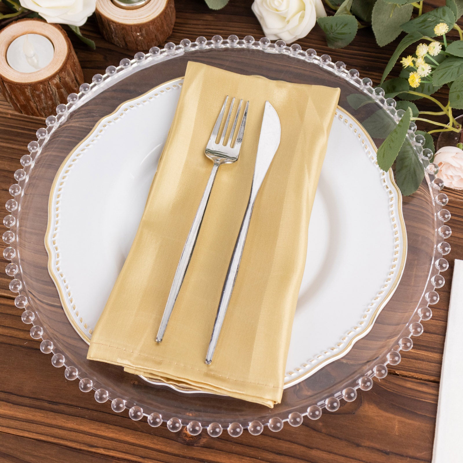Champagne satin linen napkins on a table setting with silver utensils.